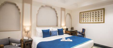 Habitación de hotel con una cama grande, un escritorio, una silla y un panel de llaves en la pared.