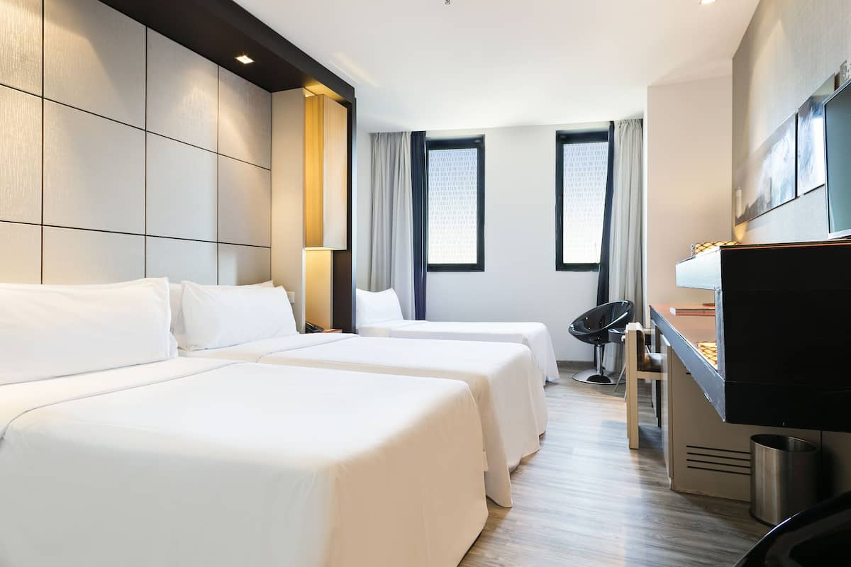 Une chambre d’hôtel avec deux lits, un bureau, une chaise et un téléviseur.