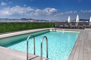 Una piscina al aire libre de temporada, sombrillas, tumbonas