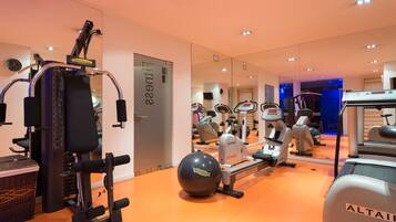 A gym with various exercise equipment, including a rowing machine, elliptical, and stationary bikes.