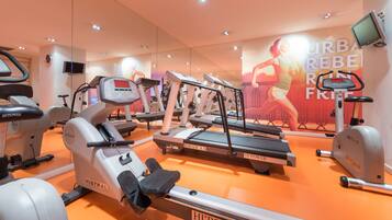 Un gimnasio con cintas de correr, elípticas y un muro de espejos con carteles motivacionales.