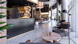 En modern hotellobby med en receptionsdisk, en sittgrupp och en bar.