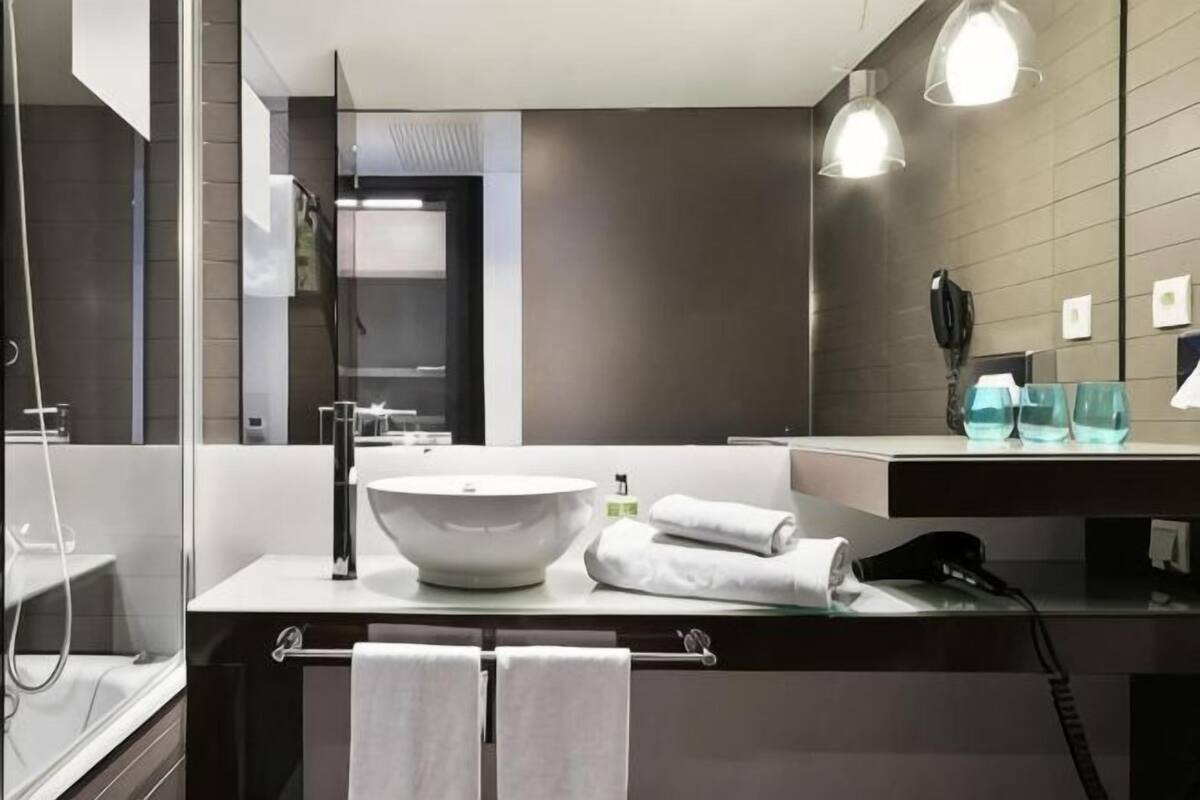Une salle de bain moderne avec un grand lavabo, un porte-serviettes et un miroir.