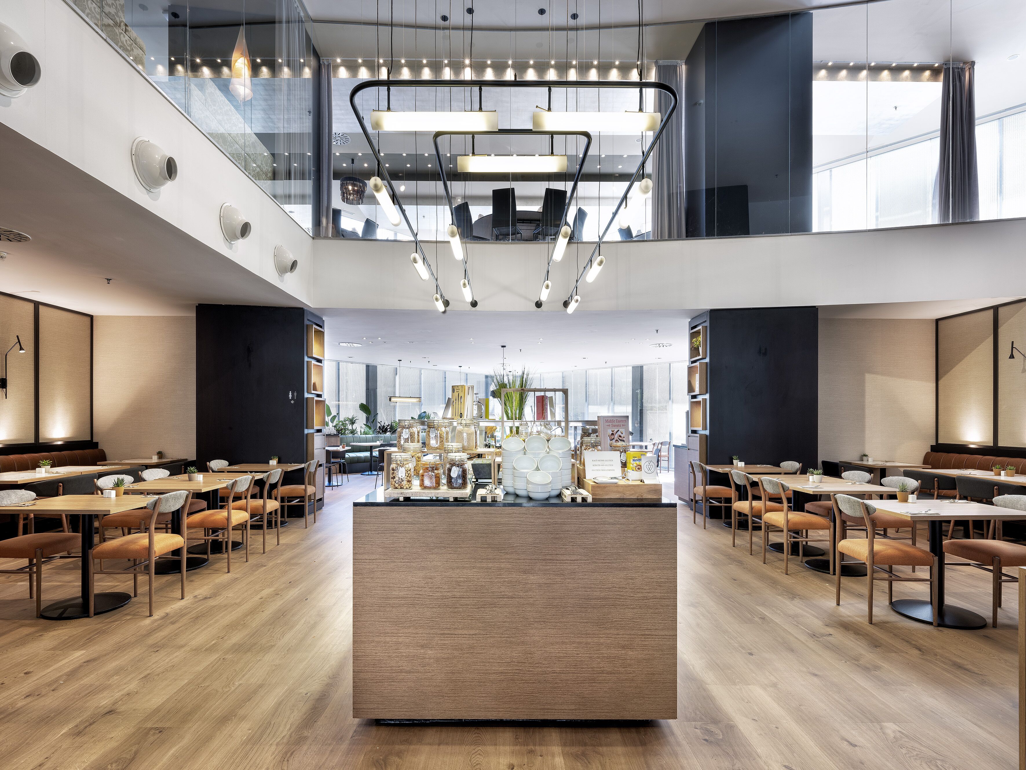 Un restaurant spacieux doté de plusieurs espaces de restauration, d’un comptoir central et d’un design moderne au niveau du plafond.