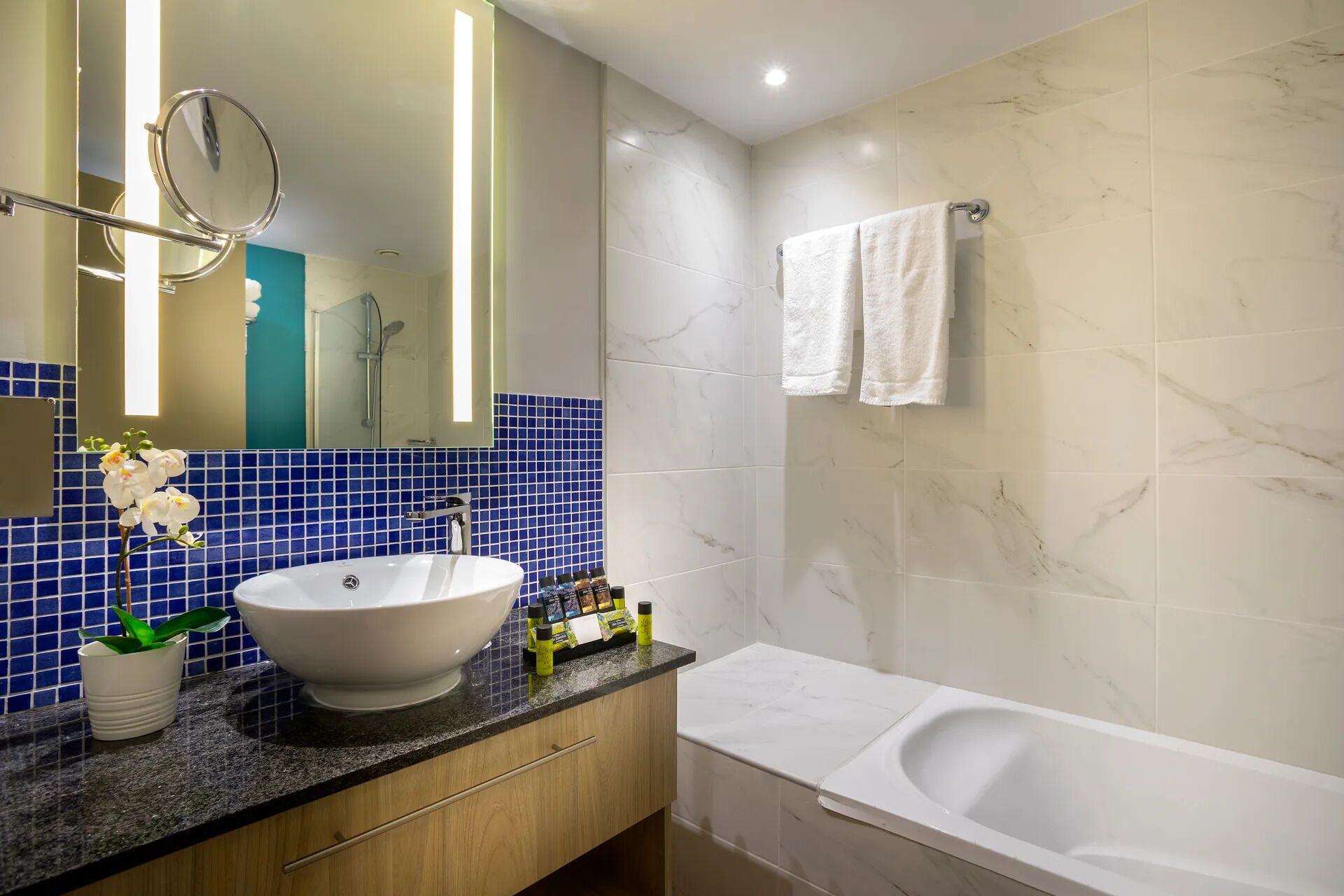 A bathroom with a white sink, a bathtub, and a mirror.