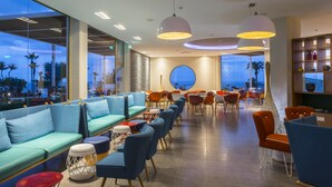 Un espace lounge moderne avec des sièges, un bar et une vue sur l’océan.