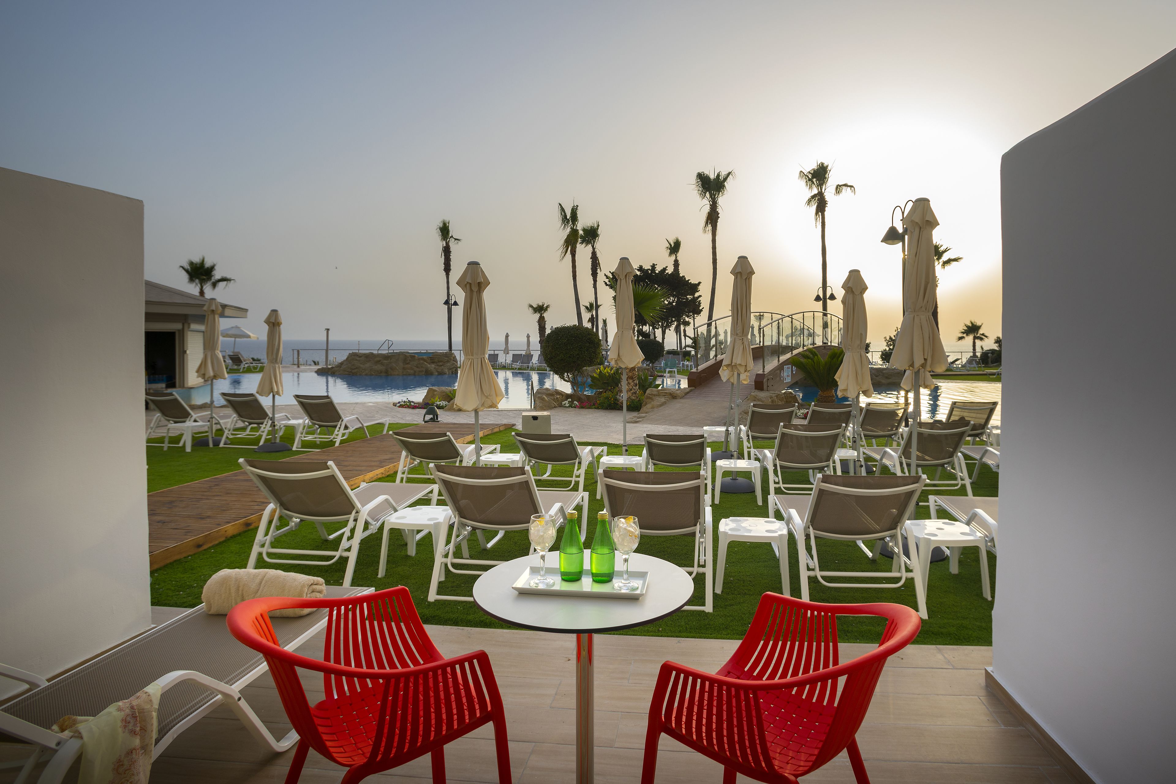 A poolside area with lounge chairs, a table with bottles, and umbrellas.
