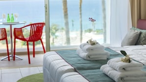 Une chambre d’hôtel avec un lit, une vue sur la mer et une table avec des chaises à l’extérieur.