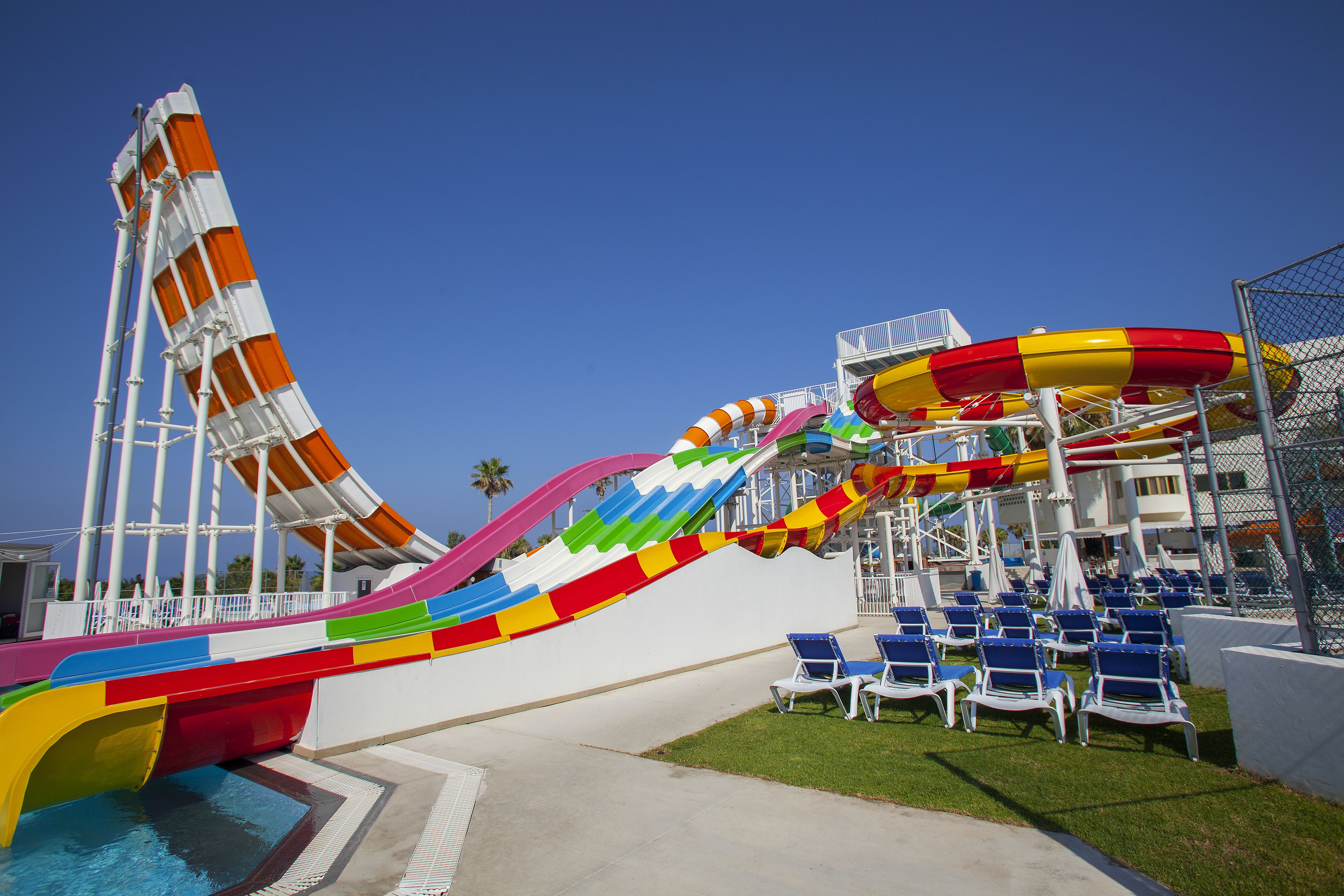 Parque acuático con múltiples toboganes y zona de piscina con sillones de descanso.