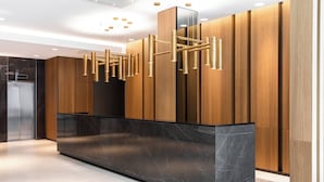 A modern reception area with a marble counter, wooden paneling, and a unique hanging light fixture. - AC Hotel by Marriott Riga (Riga)