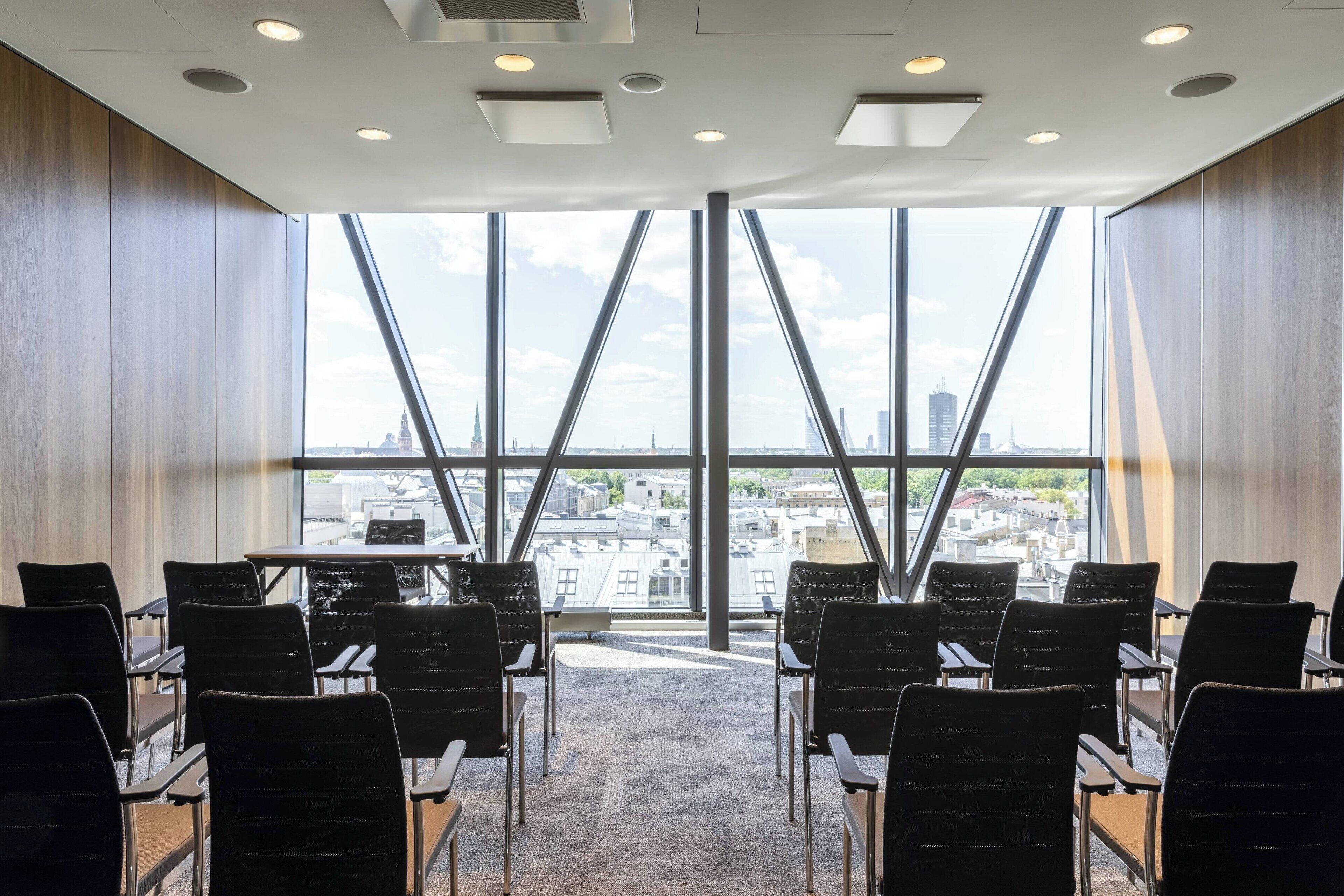 Uma sala de conferências com vista para a cidade, grandes janelas e móveis modernos.