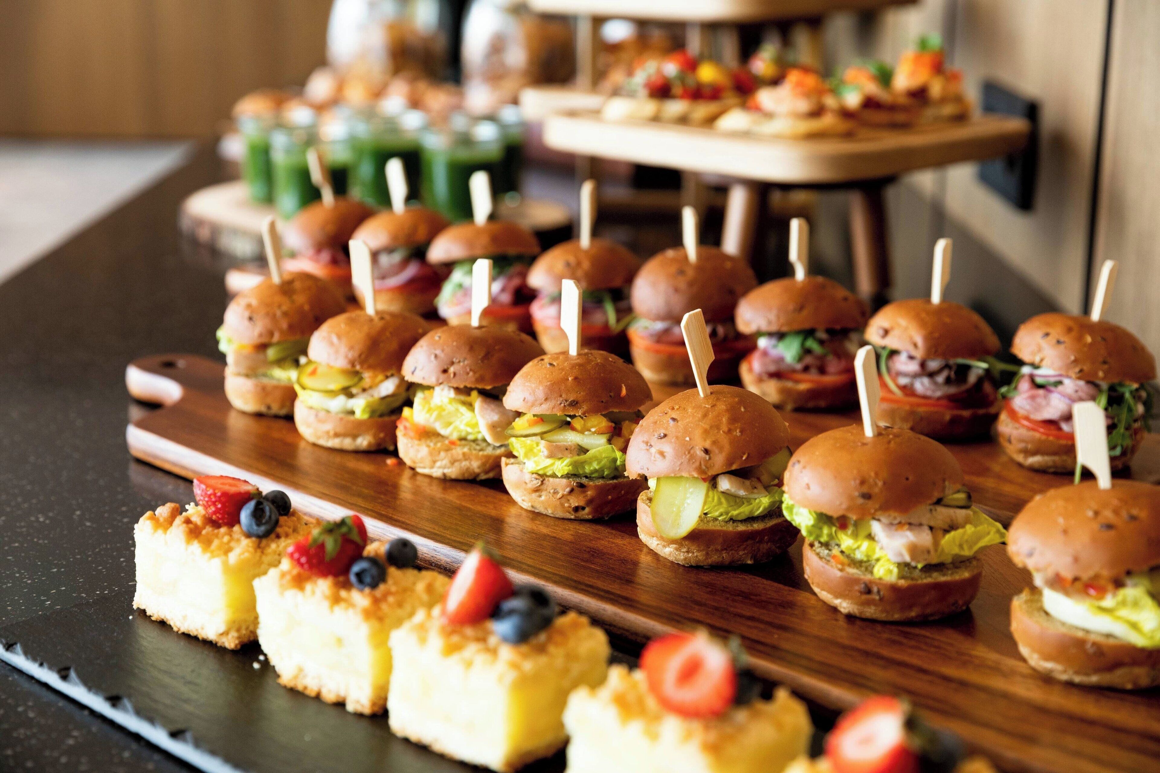 Una mesa de buffet con sándwiches pequeños y pequeñas pastas.