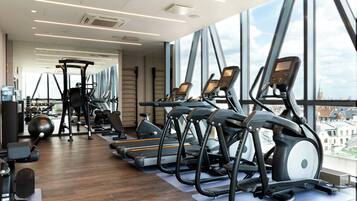 Un gimnasio moderno con cintas de correr, elípticas y pesas sueltas.