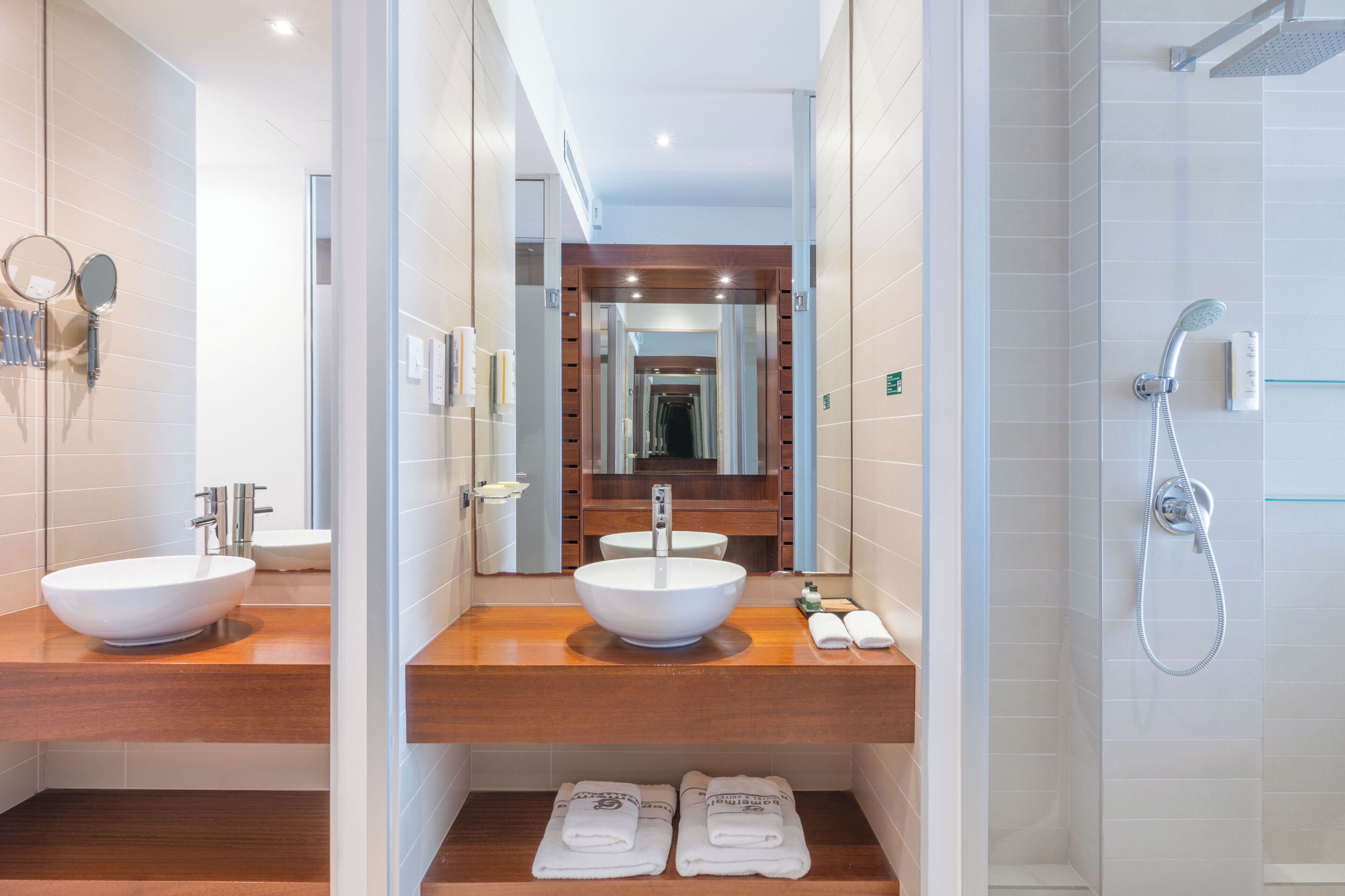 Une salle de bain moderne avec deux lavabos, une douche et un miroir.