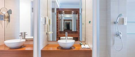 Une salle de bain moderne avec deux lavabos, une douche et un miroir.