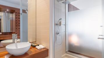 Een moderne badkamer met een groot wit wastafel, een douchecabine van glas en een houten wastafelmeubel.