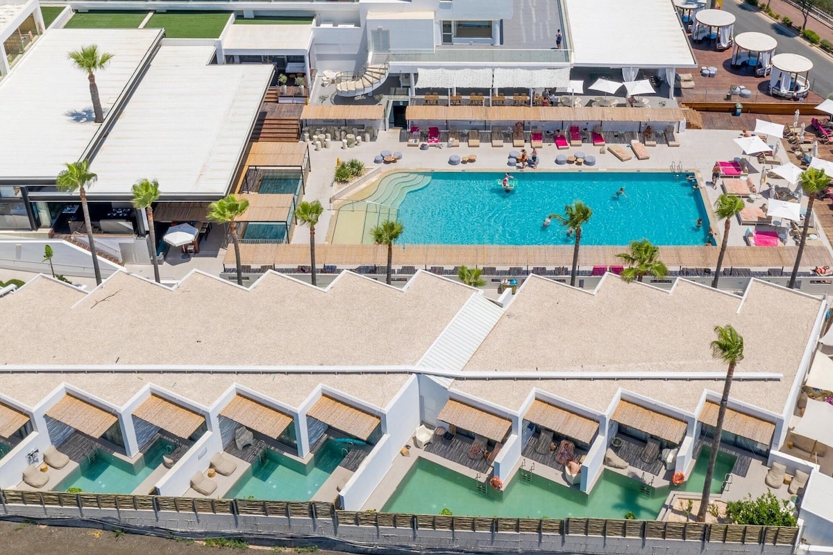 Vue aérienne d’un hôtel doté de plusieurs piscines, d’espaces de détente en plein air et d’un grand patio couvert.