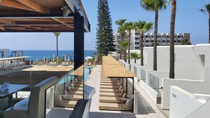 A rooftop pool area with lounge chairs and tables, overlooking the ocean. - Napa Mermaid Hotel & Suites (Ayia Napa)