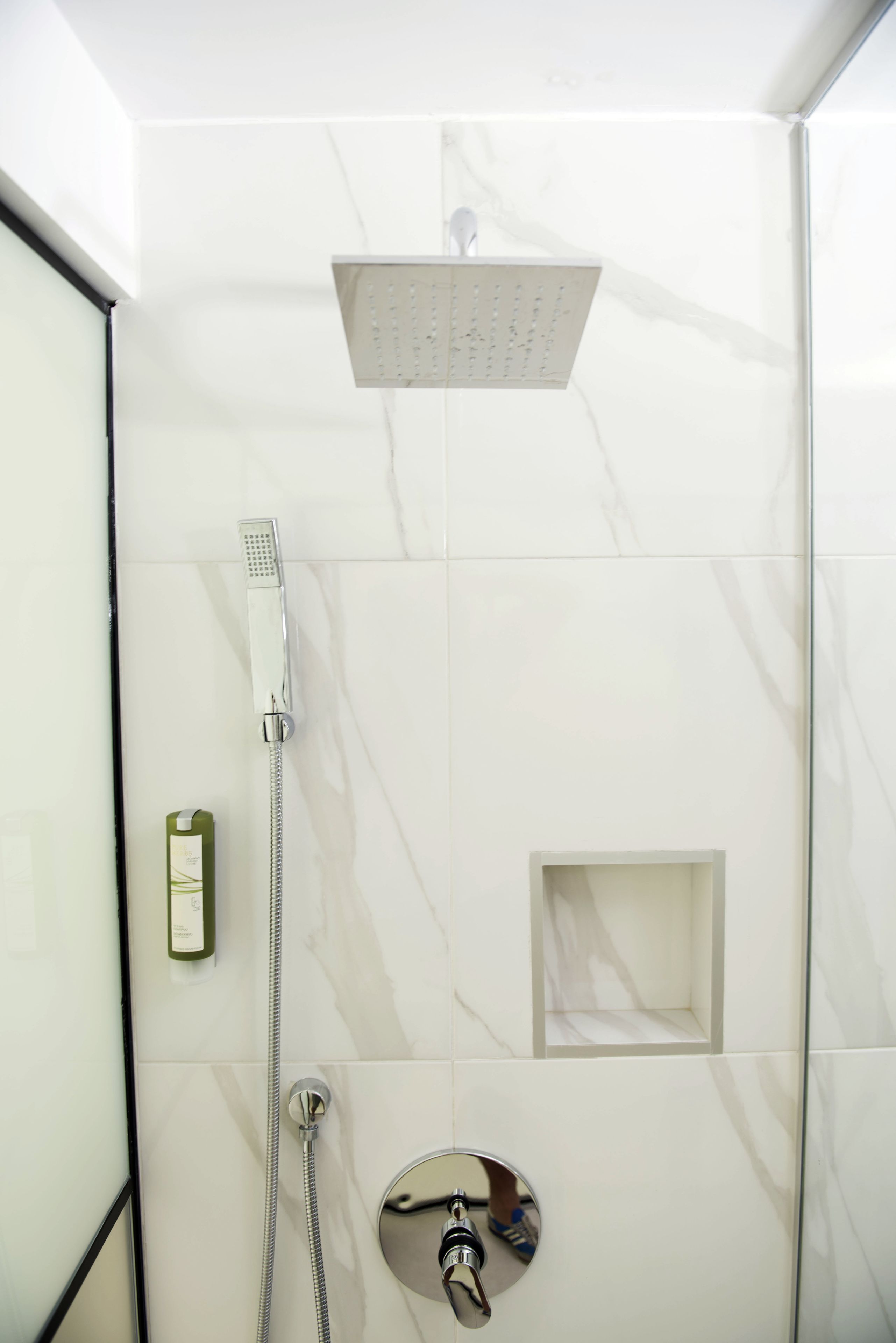 Une douche moderne équipée d’un pommeau de douche à main et d’un pommeau de douche fixe au plafond.