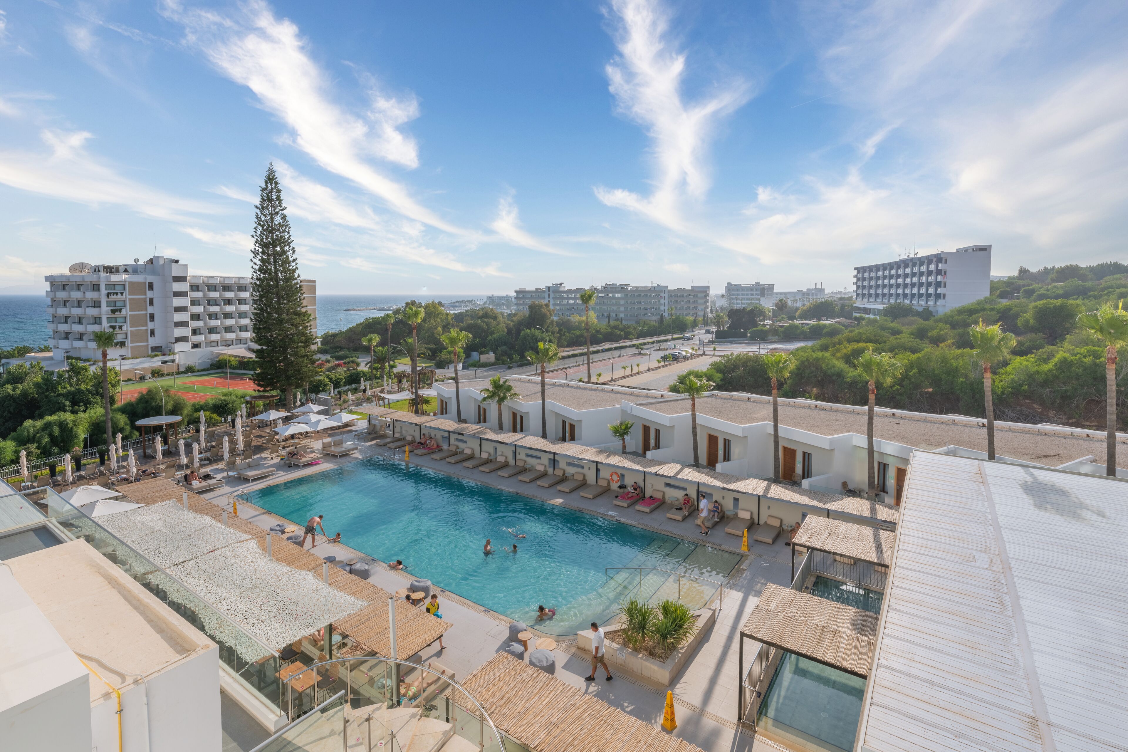 Un hotel con piscina, mobiliario exterior y vistas al mar.