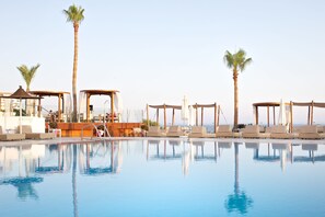 A pool with lounge chairs and palm trees, surrounded by a wooden deck and a gazebo. - Napa Mermaid Hotel & Suites (Ayia Napa)
