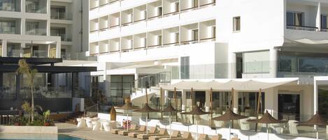 Un hôtel moderne doté d’une piscine, de plusieurs balcons et de chaises longues.