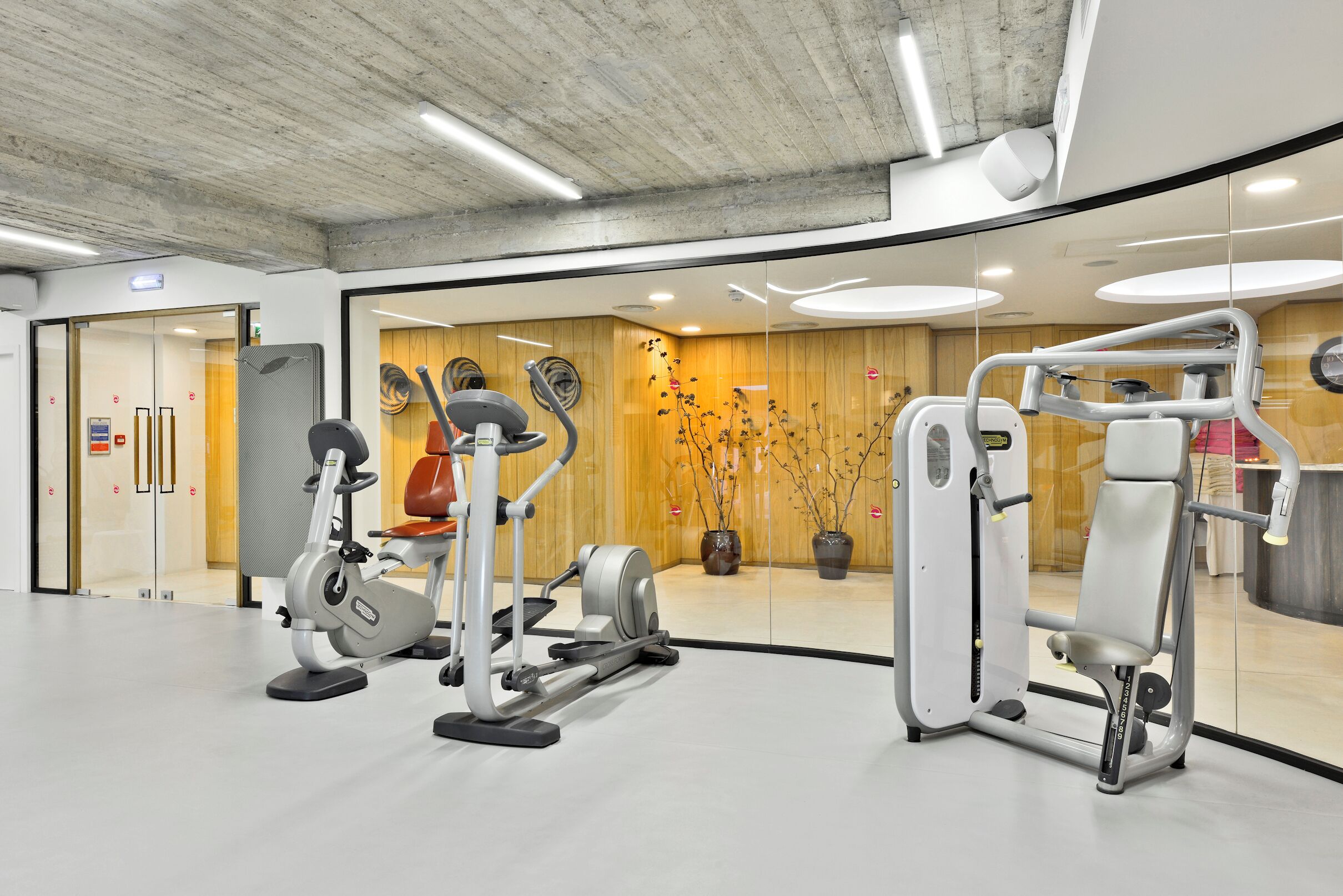 A modern gym with various exercise equipment, including a stationary bike, elliptical, and weight machines.