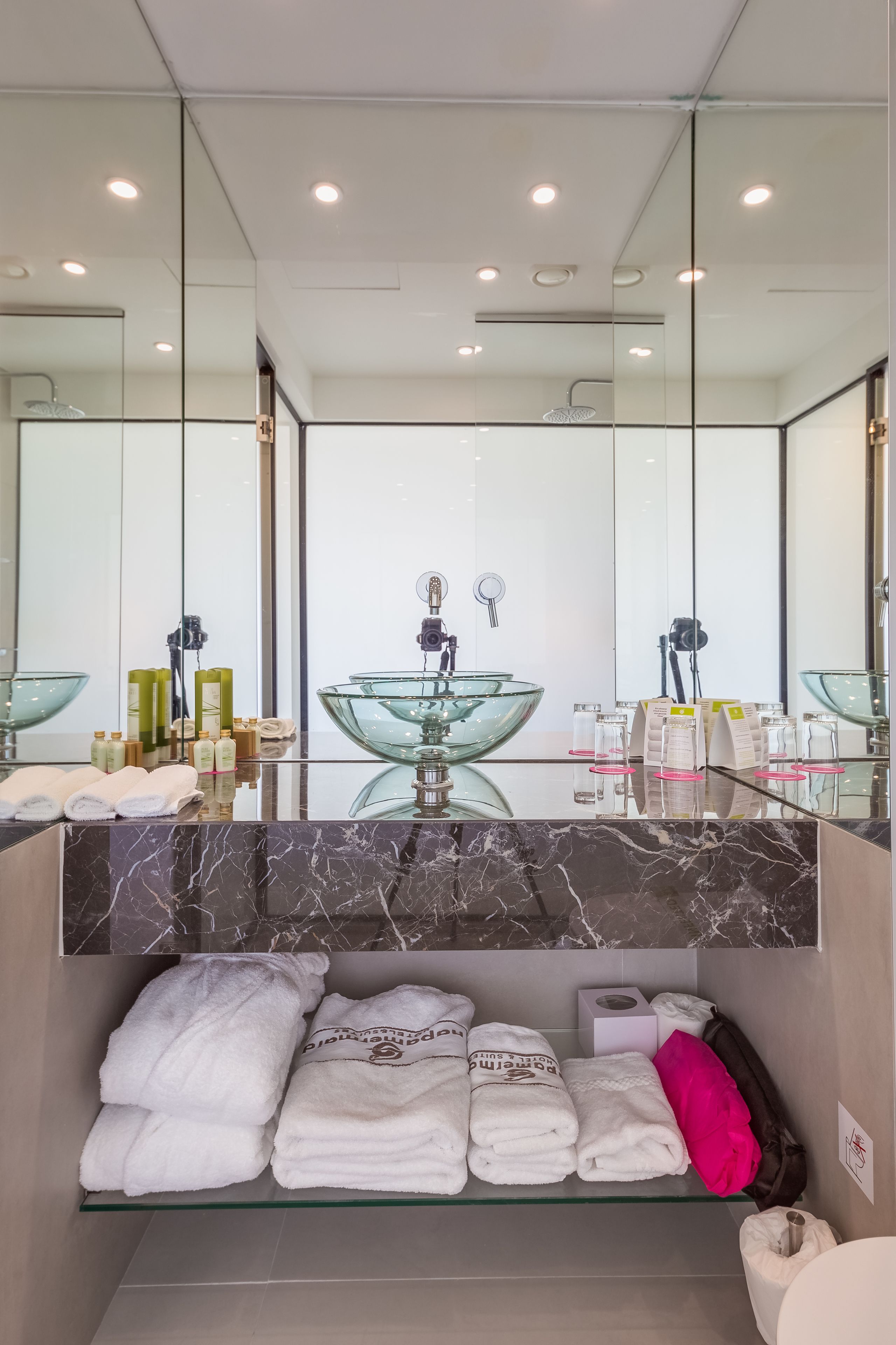 Un baño moderno con un lavabo de vidrio, encimera de mármol y toallas dobladas con esmero.