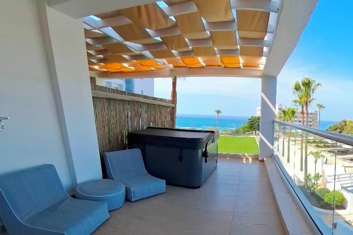 Un balcon avec une table de billard, deux canapés bleus et une vue sur l’océan.