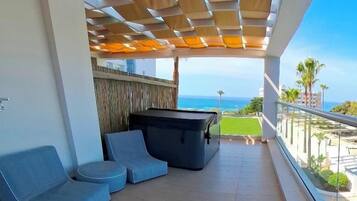 A balcony with a pool table, two blue sofas, and a view of the ocean.