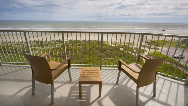 A balcony with two chairs and a small table, overlooking a beach and ocean. - Holiday Inn Club Vacations Galveston Beach Resort by IHG (Galveston)