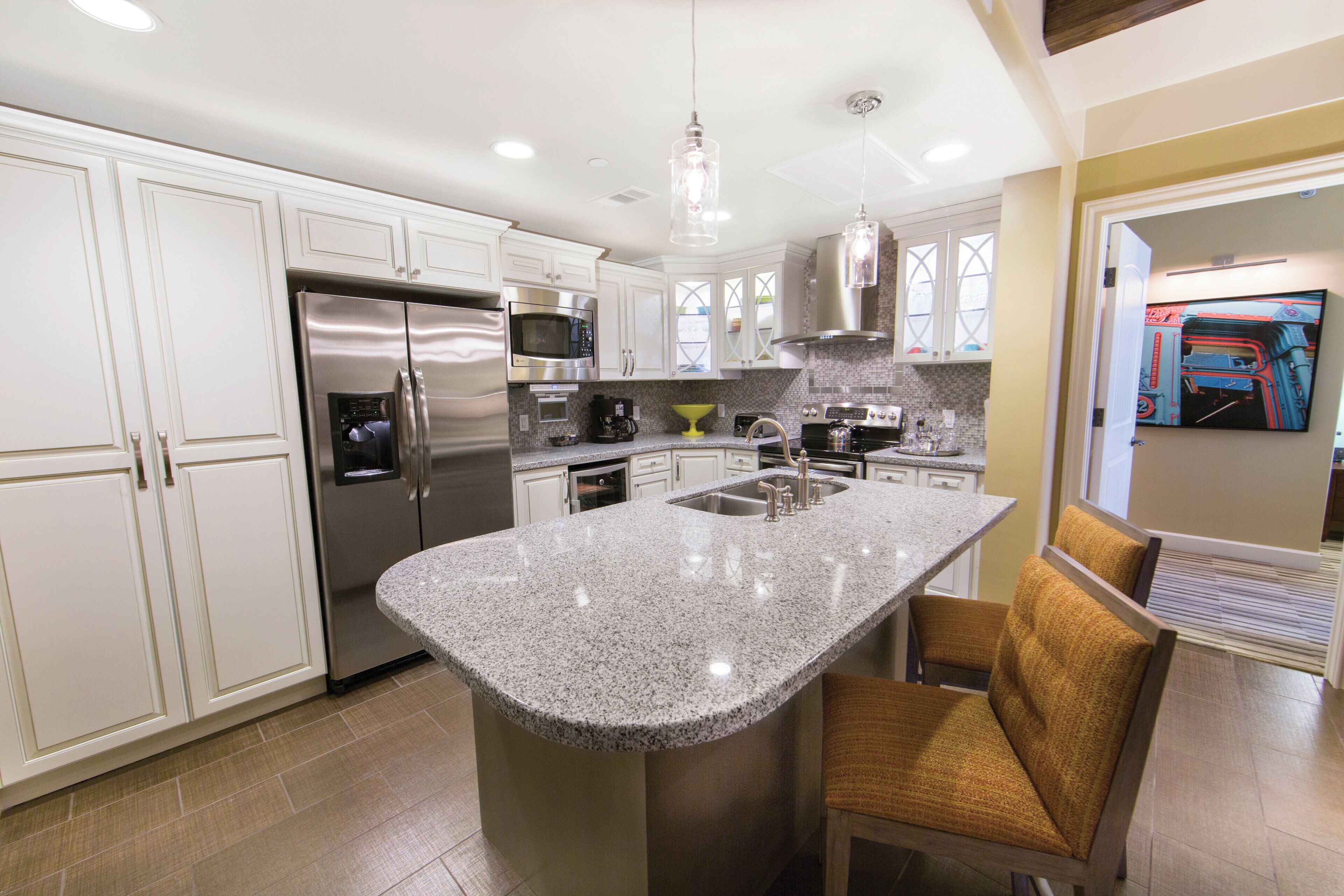 A modern kitchen with stainless steel appliances, a granite countertop island, and a built-in oven.
