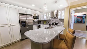 A modern kitchen with stainless steel appliances, a granite countertop island, and a built-in oven.