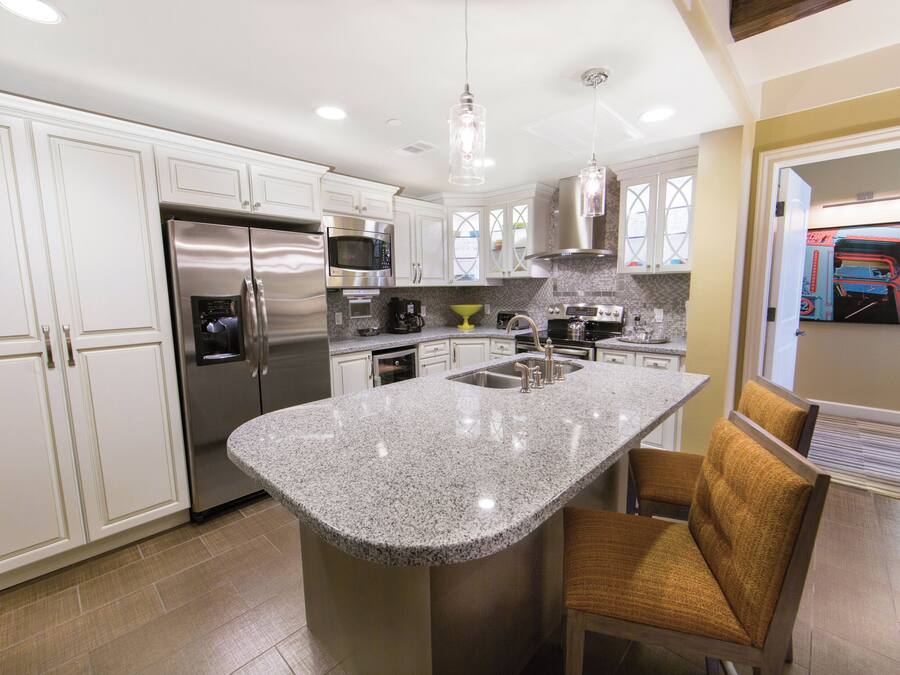 A modern kitchen with stainless steel appliances, a granite countertop island, and a built-in oven.