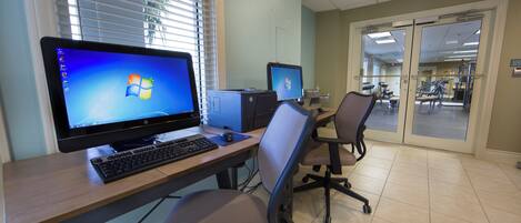 Un poste de travail informatique comprenant deux écrans, un clavier et une chaise.