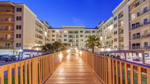 A wooden walkway leading to a multi-story building with balconies and a central courtyard. - Holiday Inn Club Vacations Galveston Beach Resort by IHG (Galveston)