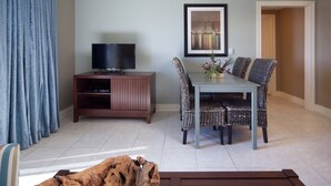 A living room with a TV, dining table, wicker chairs, and a framed picture on the wall. - Holiday Inn Club Vacations Galveston Beach Resort by IHG (Galveston)