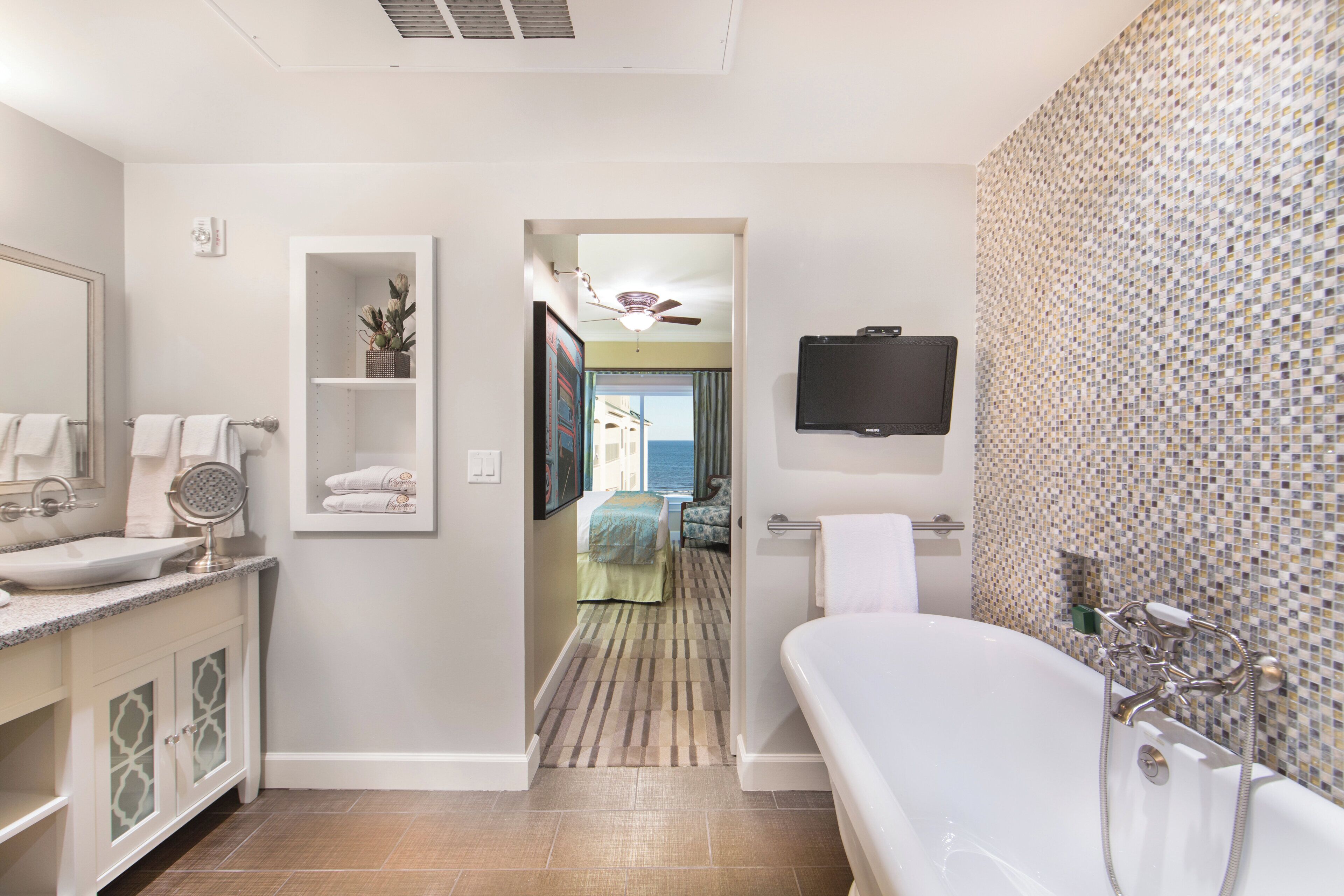 A modern bathroom with a freestanding bathtub, a large mirror, a vanity with a sink, and a shower area.