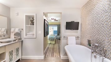 A modern bathroom with a freestanding bathtub, a large mirror, a vanity with a sink, and a shower area.