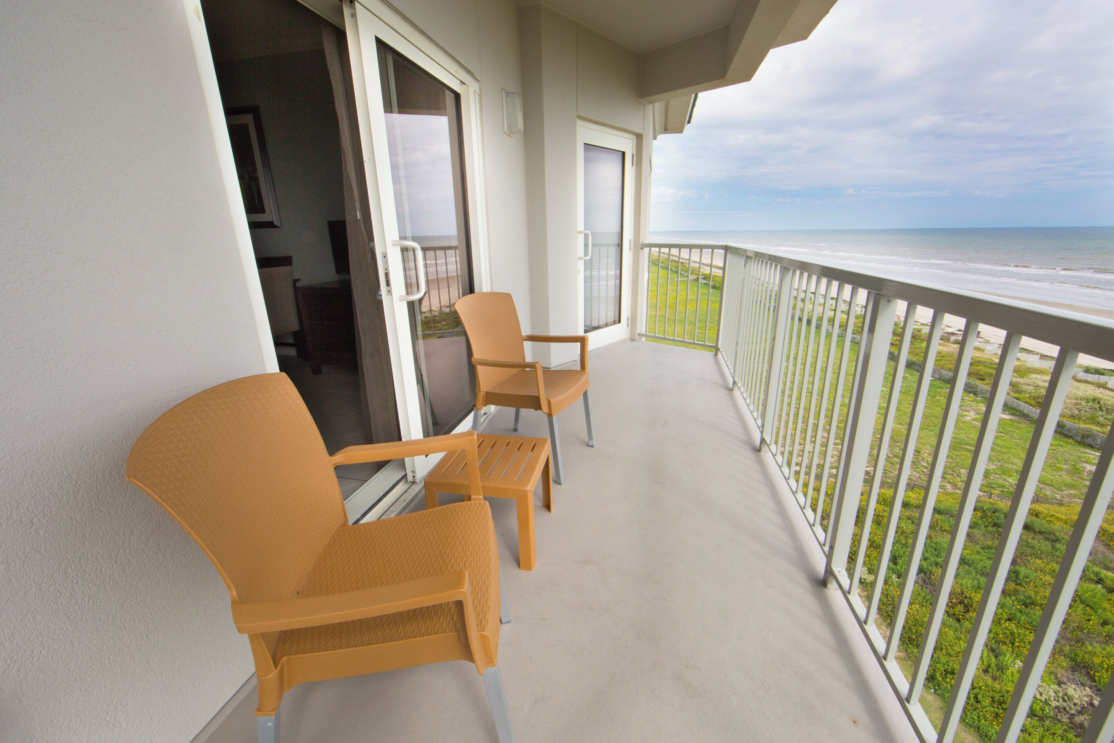 Un balcon avec deux chaises et une porte donnant sur un espace intérieur.