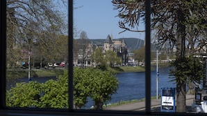 A view of a historic building with a large tower and a church-like structure across a river.