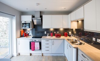 Una cocina moderna con armarios blancos, un lavamanos de acero inoxidable y un horno empotrado.