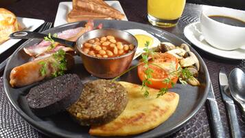 A breakfast plate with beans, sausage, toast, and a slice of tomato.