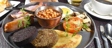 A breakfast plate with beans, sausage, toast, and a slice of tomato.