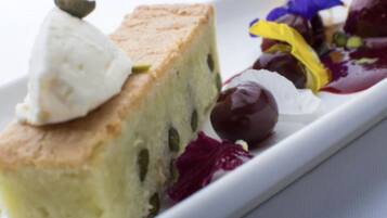 A slice of cake with a dollop of cream on top, accompanied by a side of mixed berries and a small dollop of cream.