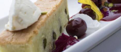 A slice of cake with a dollop of cream on top, accompanied by a side of mixed berries and a small dollop of cream.