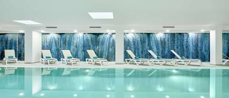 Una piscina con sdraio e un muro decorato con un'immagine blu.