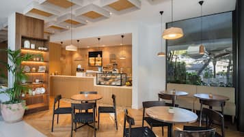A modern cafe interior with wooden flooring, round tables, and black chairs.