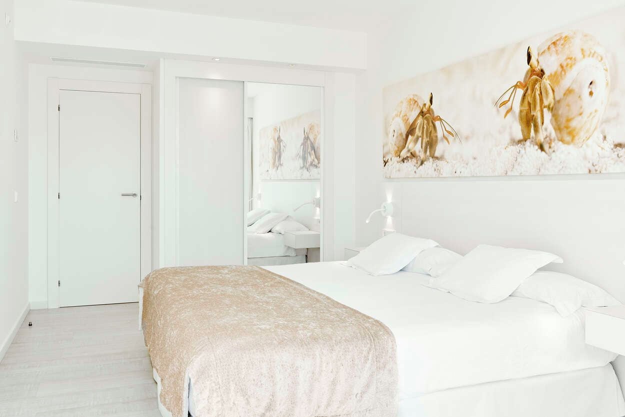 A hotel room with a bed, a white door, and a large painting on the wall.