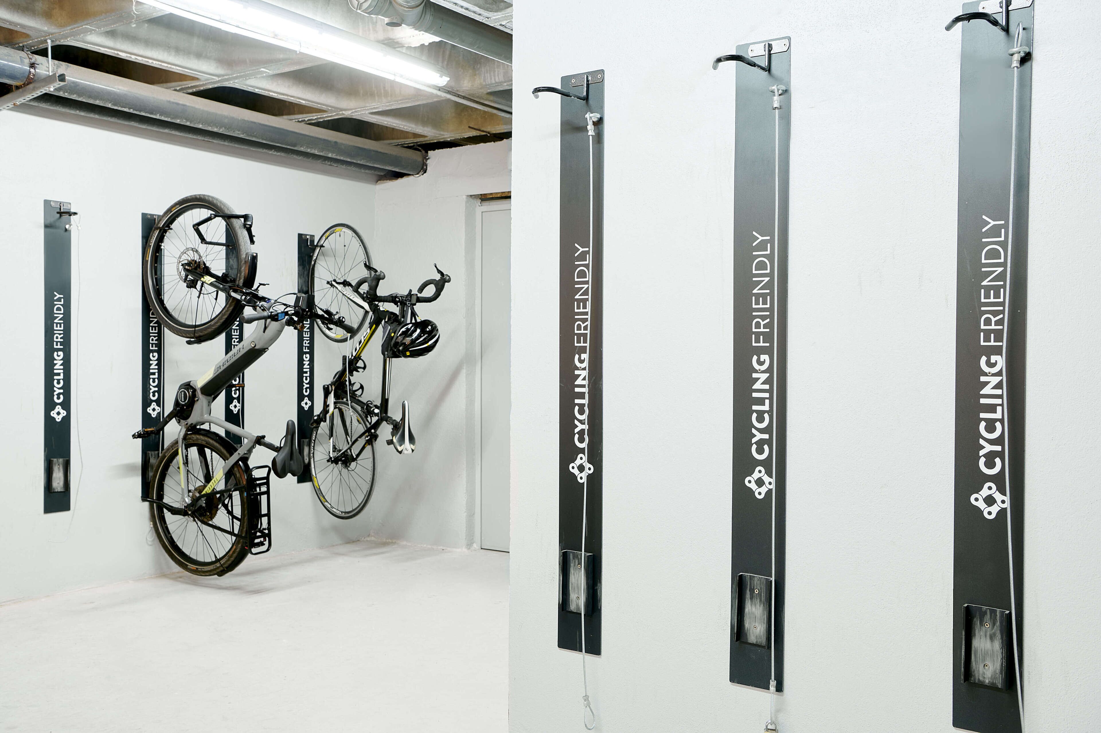 Un espacio para guardar bicicletas con varias bicicletas y letreros verticales que indican "CYCLING FRIENDLY".
